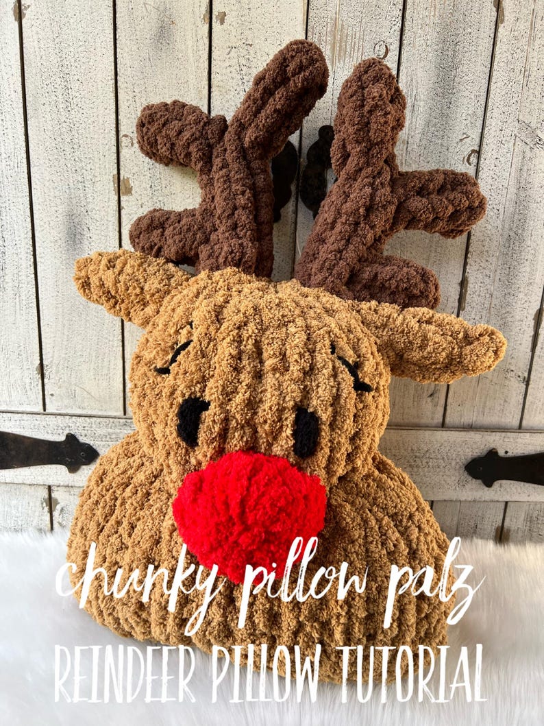 May include: A handmade, plush reindeer pillow with brown antlers, tan body, black eyes, and a red nose. The pillow has the words "chunky pillow palz" and "REINDEER PILLOW TUTORIAL" in white script.