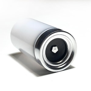 Op de afbeelding: Een witte cilindrische flessenstop met een zilveren dop en een zwart midden met een zeshoekig ontwerp.