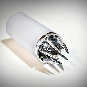 Puede incluir: Objeto cilíndrico de vidrio esmerilado con base de metal plateado y un diseño complejo de múltiples puntas. El objeto es probablemente una herramienta de cocina, como un abridor de botellas.