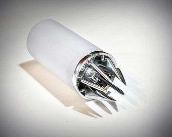 May include: A cylindrical, frosted glass object with a silver-colored metal base and a complex, multi-pronged design. The object is likely a kitchen tool or gadget, possibly a bottle opener or similar item.