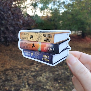 Pode incluir: Uma pilha de três livros de bolso com fundo branco. Os livros são intitulados "Fourth Wing", "Iron Flame" e "Onyx Storm". A autora é Rebecca Yarros.