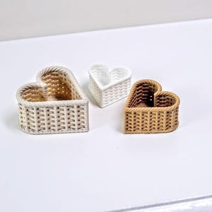 Peut inclure: Trois paniers en osier en forme de cœur de différentes tailles. Le plus grand panier est blanc, le panier moyen est blanc et le plus petit panier est brun.