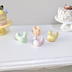 Può includere: Quattro pulcini in ceramica color pastello, in tonalità di verde, rosa, giallo e arancio, sono disposti su una superficie bianca. I pulcini sono tutti rivolti in avanti e hanno le ali spiegate.