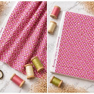 May include: Pink fabric with an oval pattern, spools of thread in pink, cream, and green, and a pair of scissors. The fabric has the text "Freshcut" and "Heather Ross" printed on the edge. The fabric is folded and laid out on a white surface.