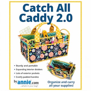 May include: A Catch All Caddy 2.0 storage organizer featuring a dark blue fabric with a floral pattern of pink and white flowers. The caddy has yellow polka dot handles and trim, multiple exterior pockets, and interior dividers holding various supplies.