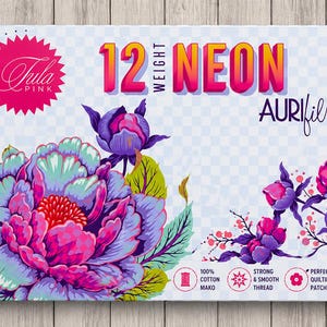 Op de afbeelding: Een rechthoekige doos met Tula Pink branding en de tekst 12 WEIGHT NEON AURIFIL. Het ontwerp toont grote, levendige paarse en roze pioenroosachtige bloemen met groene bladeren tegen een lichtblauwe ruitjesachtergrond. Inclusief productdetails.