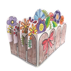 K&ouml;nnte beinhalten: Ein brauner Papier-Blumentopf mit einem Zaunmuster. Der Topf ist mit bunten Papierblumen gef&uuml;llt, darunter lila, gelbe, rote und blaue Blumen.
