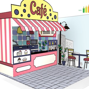 Puede incluir: Un modelo de papel de una cafetería con un exterior a rayas rosa y blanco, un toldo amarillo con la palabra "Café" en letras negras y una pequeña zona de asientos al aire libre con dos mesas y sillas. La cafetería tiene una ventana con vista a un horizonte urbano.