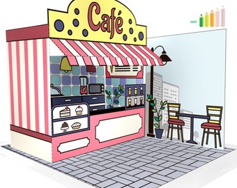 May include: A papercraft model of a cafe with a pink and white striped exterior, a yellow awning with the word "Cafe" in black lettering, and a small outdoor seating area with two tables and chairs. The cafe has a window with a view of a city skyline.