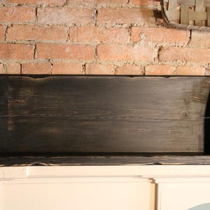 Peut inclure: Une &eacute;tag&egrave;re rectangulaire en bois noir avec une finition vieillie. L'&eacute;tag&egrave;re a un design peu profond avec des c&ocirc;t&eacute;s sur&eacute;lev&eacute;s et est mont&eacute;e contre un mur de briques rouges. L'&eacute;tag&egrave;re mesure environ 76 cm de long.
