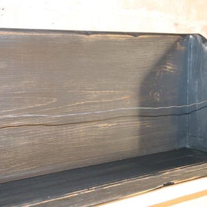 Peut inclure: &Eacute;tag&egrave;re en bois fonc&eacute; avec une finition vieillie. De forme rectangulaire, elle pr&eacute;sente un devant l&eacute;g&egrave;rement inclin&eacute; et un grain de bois visible. La couleur est un charbon profond avec des reflets plus clairs.
