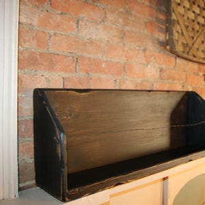 Peut inclure: &Eacute;tag&egrave;re rectangulaire en bois sombre et vieilli, fix&eacute;e contre un mur de briques rouges. Le design est simple et fonctionnel. Ses dimensions sont d'environ 61 cm de long, 20 cm de haut et 15 cm de profondeur, id&eacute;ale pour la d&eacute;coration.