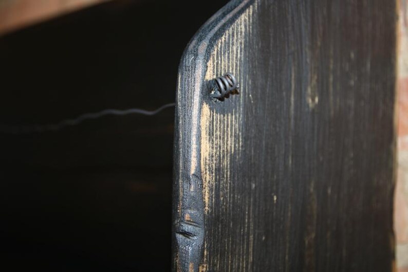 Peut inclure: Gros plan sur une section d'un objet en bois teint&eacute; fonc&eacute;. Le grain du bois est visible, avec une fixation m&eacute;tallique sur le c&ocirc;t&eacute;. L'objet semble faire partie d'un meuble ou d'un &eacute;l&eacute;ment de d&eacute;coration plus grand.