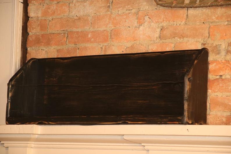 Peut inclure: &Eacute;tag&egrave;re en bois teint&eacute; fonc&eacute; avec un dessus inclin&eacute; et une forme rectangulaire. L'&eacute;tag&egrave;re est mont&eacute;e sur une surface blanche contre un mur de briques. L'&eacute;tag&egrave;re est con&ccedil;ue pour le stockage ou l'affichage.