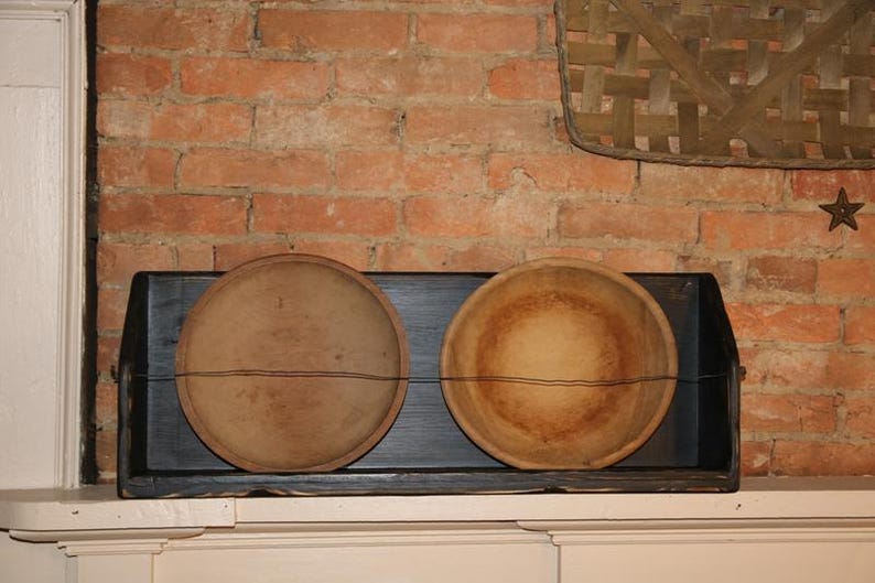 Peut inclure: Deux bols en bois antiques, l'un une assiette et l'autre un bol, sont expos&eacute;s dans une &eacute;tag&egrave;re en bois noir. Les bols sont brun clair avec des accents de fil brun fonc&eacute;, sur un mur de briques rustique.