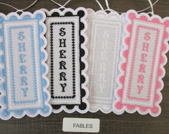 May include: Four embroidered fabric bookmarks with the word "SHERRY" spelled vertically in different colors. The bookmarks are white with blue, black, white, and pink borders.