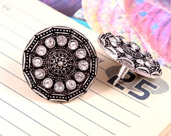 May include: A pair of silver earrings with a round design. The earrings are decorated with small, clear rhinestones.
