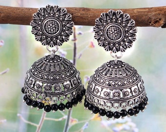May include: A pair of silver earrings with black beads. The earrings feature a round, ornate design with a floral pattern.