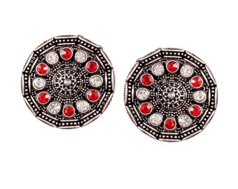 May include: A pair of silver earrings with a circular design. The earrings are adorned with red and white rhinestones.