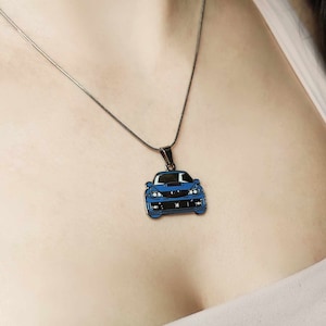 Könnte beinhalten: Eine silberne Kettenkette mit einem blauen Auto-Anhänger. Das Auto ist ein Subaru Impreza WRX STI.
