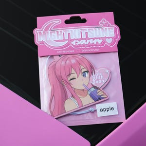 May include: Pink air freshener featuring an anime girl with pink hair drinking boba tea. The air freshener has the text "NIGHTKITSUNE" and "apple". A car accessory.