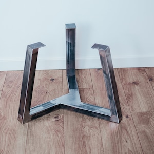 Pode incluir: Uma base de mesa de metal com três pernas. As pernas são feitas de metal retangular grosso e são soldadas juntas na parte inferior para formar uma forma triangular.