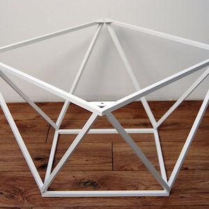 Könnte beinhalten: Weißer geometrischer Tischfuß aus Metall mit quadratischer Platte und rautenförmigem Rahmen.