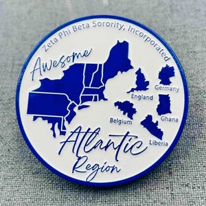 Peut inclure: Épinglette ronde blanche et bleue de la Zeta Phi Beta Sorority, Incorporated. Elle présente un contour bleu de la région Atlantique, avec les mots "Awesome" et "Atlantic Region". Elle comprend également les contours de l'Angleterre, de l'Allemagne, de la Belgique, du Ghana et du Libéria.