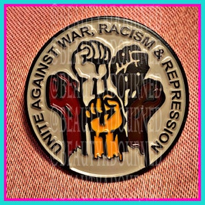 May include: A round pin with the text "UNITE AGAINST WAR, RACISM & REPRESSION" encircling a design of raised fists in red, orange, white, and brown. The pin has a black border and a light gray background.