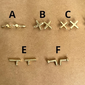 Peut inclure: Assortiment de boutons et de poignées de tiroir en or dans différents styles, y compris en forme d'étoile, de croix et de T.