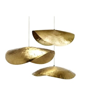 May include: Three gold-toned metal pendant lights, each shaped like a curved, shallow bowl, hang from the ceiling.