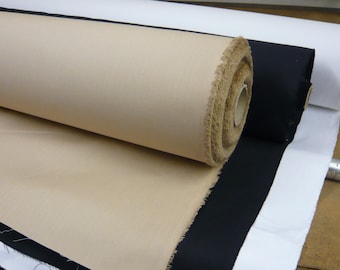 Op de afbeelding: Twee rollen stof, een beige en een zwarte, zijn opgerold en op elkaar gelegd. De beige stof ligt bovenop en de zwarte stof eronder.
