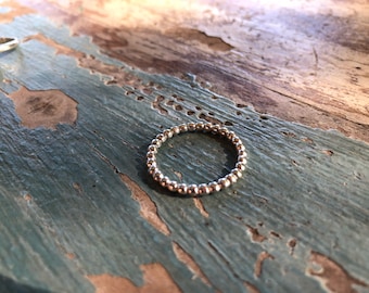 Puede incluir: Un anillo de plata con cuentas sobre una superficie de madera desgastada.
