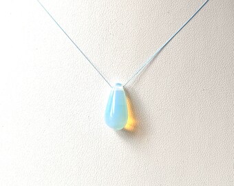 Puede incluir: Un colgante de ópalo en forma de lágrima en una cadena de plata. El ópalo es de color azul claro con un toque de amarillo.