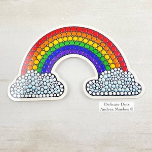 May include: A rainbow sticker with white clouds, made with colorful dots. The sticker says "Delicate Dots Andrea Moebes ©".