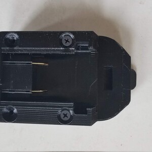 May include: Black plastic battery connector with two gold-colored contacts and two screws.