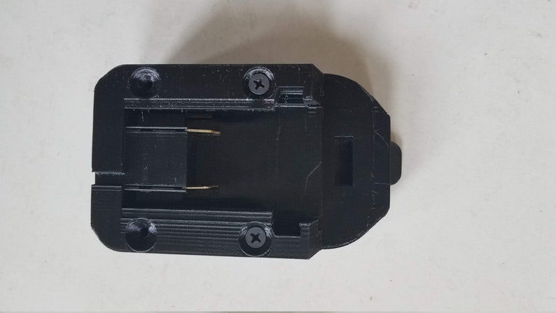 May include: Black plastic battery connector with two gold-colored contacts and two screws.