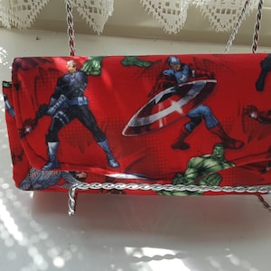 Puede incluir: Cartera de tela roja con estampado de varios superhéroes, entre ellos Capitán América, Iron Man y Hulk.
