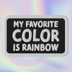Op de afbeelding: Zwarte geborduurde patch met witte tekst die "Mijn favoriete kleur is regenboog" luidt.