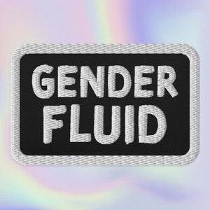 May include: A black and white embroidered patch with the text "GENDER FLUID" in white lettering.