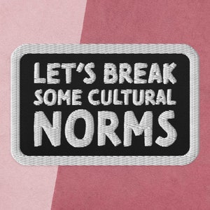 Op de afbeelding: Zwart-witte geborduurde patch met de tekst "Let's break some cultural norms" in witte letters.