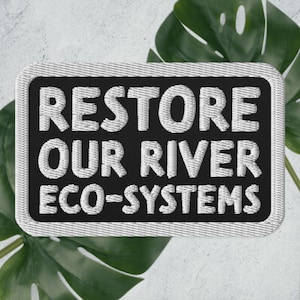 May include: White embroidered patch on a black background with the text "RESTORE OUR RIVER ECO-SYSTEMS".