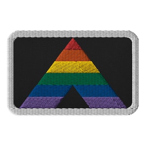 Puede incluir: Parche bordado con un diseño de triángulo arcoíris sobre fondo negro. El triángulo está formado por franjas horizontales rojas, naranjas, amarillas, verdes, azules y moradas. El parche es rectangular con un borde gris.