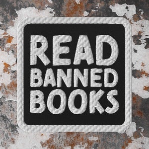 以下が含まれることがあります： 白黒の刺繍パッチで、「READ BANNED BOOKS」という文字が白で書かれています。