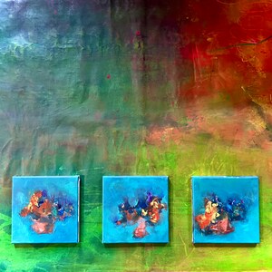 May include: Three small blue canvases with abstract paintings of colorful flowers on a green and red background.