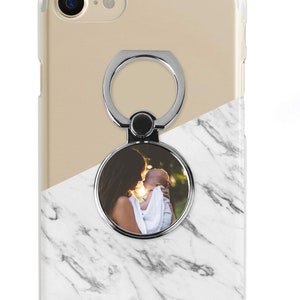 May include: A white marble phone case with a clear ring holder. The ring holder has a photo of a mother and child.