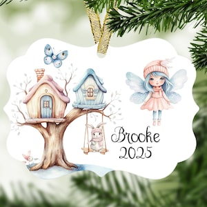 May include: Ornament with a whimsical design featuring a fairy, houses, and a bunny on a tree branch. The ornament has a gold ribbon for hanging and includes the name "Brooke" and the year "2025".