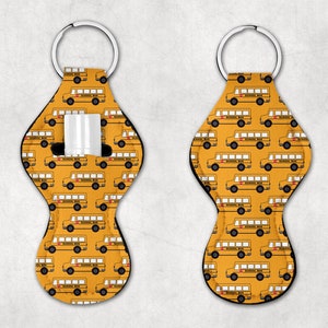 May include: Two yellow keychains with a school bus pattern. Each keychain has a loop for attaching keys and a small pocket for holding a lip balm or other small item.