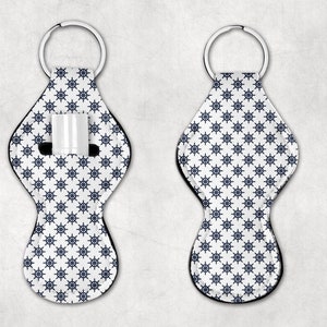 May include: White and blue key chain with a nautical wheel pattern. The key chain has a loop for attaching keys and a pocket for holding a lip balm or other small item.
