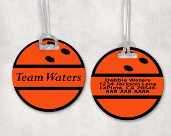 May include: Two orange luggage tags with a black bowling ball design. The tag on the left says "Team Waters". The tag on the right has the text "Debbie Waters, 1234 Jackson Lane, La Plata, CA 20646, 888-888-8888".